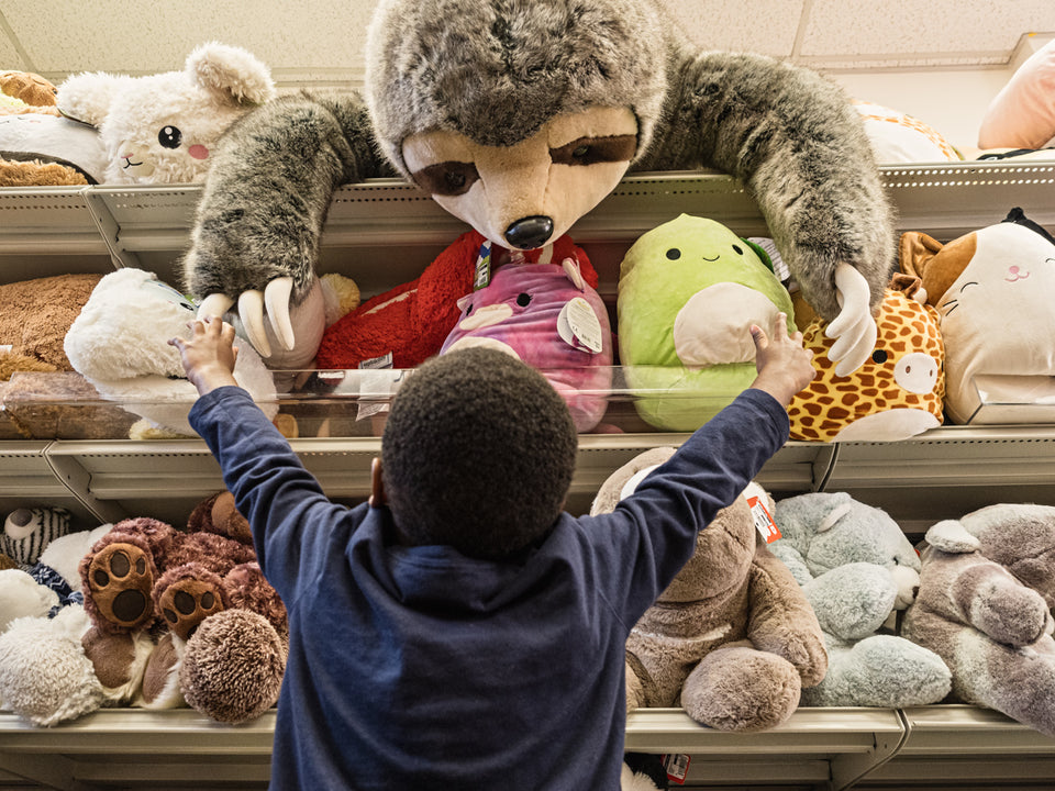 A young child reaching for a stuffed animal sloth